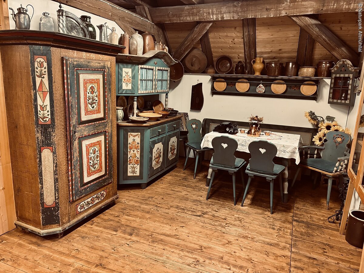 Stube Heimatmuseum Heidenheim Links sind zwei alte Bauernschränke mit bunten Verzierungen zu sehen. Rechts ein Tisch mit Stühlen