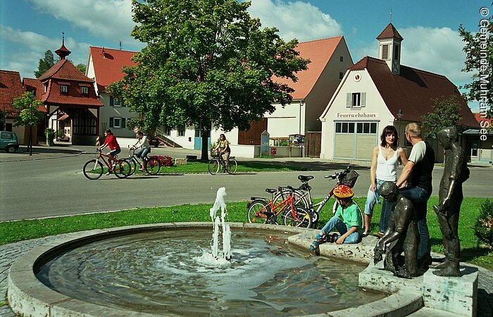 Radlpause Radler legen eine kleine Rast am Brunnen in der Ortsmitte von Muhr am Altmühlsee ein.