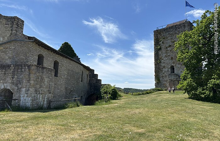 Burg Pappenheim Innenhof Im Zentrum des Bildes ist ein Innenhof zu sehen. Rechts vor einem blauen Himmel sieht man den Turm einer Burg. Links sieht man ein weiters Burggebäude.