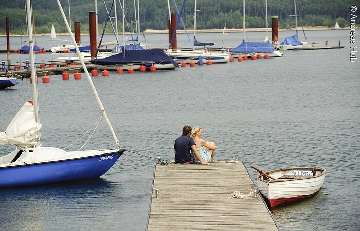 Auf dem Steg des Ramsbergers Segelhafens am Brombachsee genießen zwei Verliebte die wunderschöne Aussicht auf den Brombachsee und die Segelschiffe.