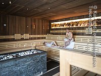 Paar befindet sich in der Panormasauna. Der Mann sitzt und die Frau liegt. Im vordergrund der Saunaofen. Paar befindet sich in der Panoramasauna. Der Mann sitzt und die Frau liegt. Im Vordergrund der Saunaofen.