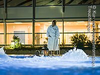 Frau im Bademantel steht, bei Dunkelheit, vor dem Sprudelbecken Frau im Bademantel steht, bei Dunkelheit, vor dem Sprudelbecken