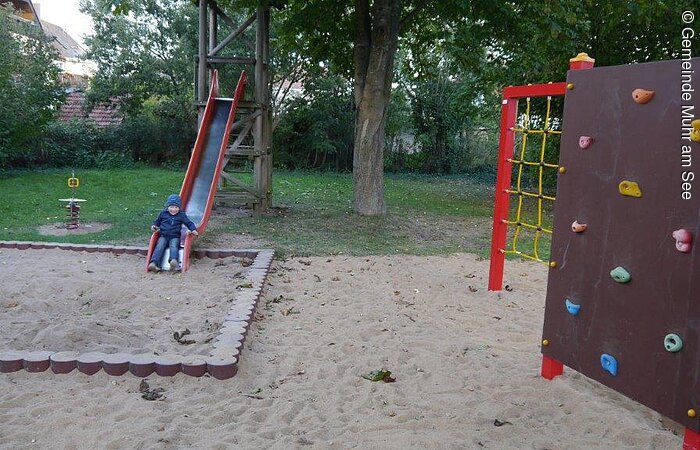 Klettergerüst mit Rutsche und Sandkasten.