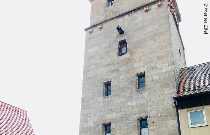 Handwerkerstuben Ein hoher Stadtturm aus Stein. Durch den Turm führt ein Stadttor.