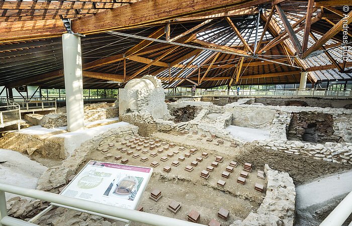 Eine gut erhaltene Bäderanlage aus der Zeit der Römer. Steinreihen bilden den Grundriss der Therme. Die Thermenanlage ist überdacht.