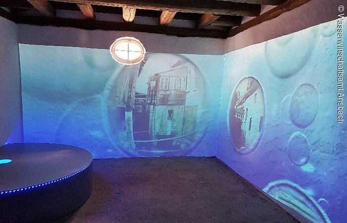 Erlebnispfad - Weg der Wasserkraft Ehemaliges Backhaus. Blaue Projektionen an den Wänden.
