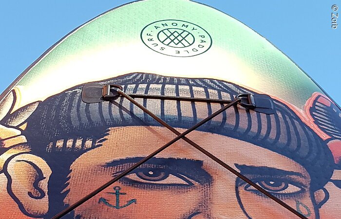 Der obere Teil eines Wakeboards. Darauf ein gemalter Mann mit braunem Bart und grauer Mütze.