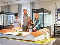 Museum Vor- und Frühgeschichte Eine Familie besucht die Abteilung der Abteilung Vor- und Frühgeschichte im Museum. Sie Blicken auf eine Nachbildung einer sogenannten Villa Rustica.