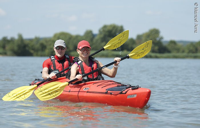 Vater und Tochter im Kajak am See und halten ihr Paddel in den Händen.