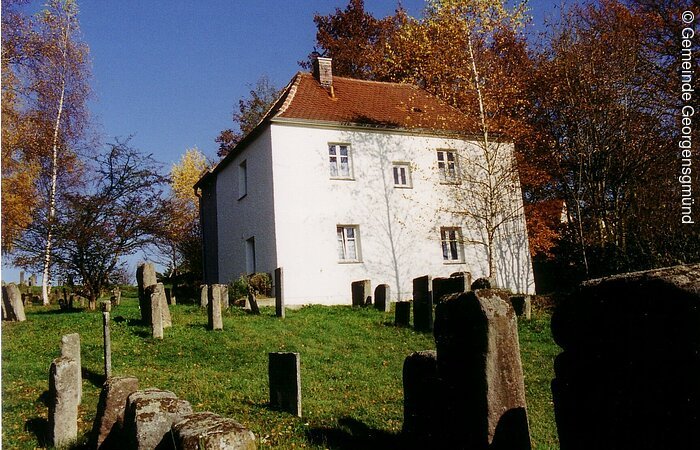 Das Georgensgmünder Taharahaus mit Judenfriedhof im Vordergrund. Das Taharahaus beinhaltet eine ehemalige Synagoge, Ritualbäder, Malereien und eine Judenschule.