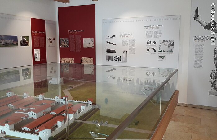 Limes Infopunkt Innenraum eines Museums. In der Raummitte ein Modell eines römischen Kastellls. An der weißen Wand Infotafeln.