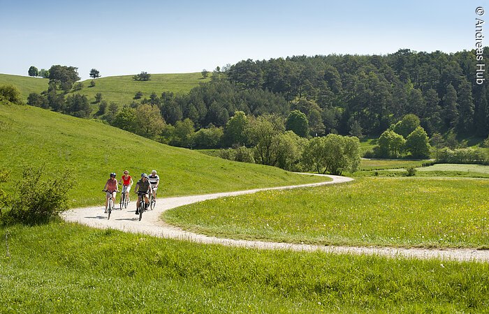 Biker auf dem Radweg im Anlautertalweg. eine Gruppe von Radfahrern radelt entlang grüner Wiesen. Vorbei an Wäldern. Der Weg schlängelt sich durch die Landschaft.