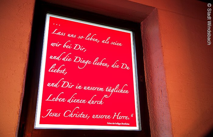 Ein rotes beleuchtetes Schild mit den Worten: Lass uns so leben, als seien wir bei dir und die Dinge lieben, die du liebst, und dir in unserem täglichen Leben dienen durch Jesus Christus, unseren Herrn!